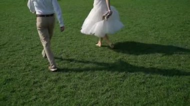 Genç bir çift parkta yürüyor. Gelin ve damat yazın