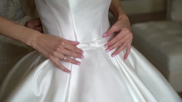 Brudtärna hjälper unga bruden att ta på sig sin bröllopsklänning. Lyxig brudklänning — Stockvideo