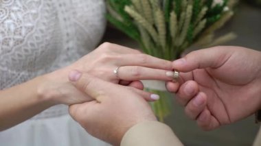 Gelin ve damat törende alyanslarını değiş tokuş ederler. Hoş bir çift.