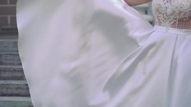 Jeune mariée en robe de mariée agitant et jetant la queue dans une ville. Mode robe de luxe blanche 