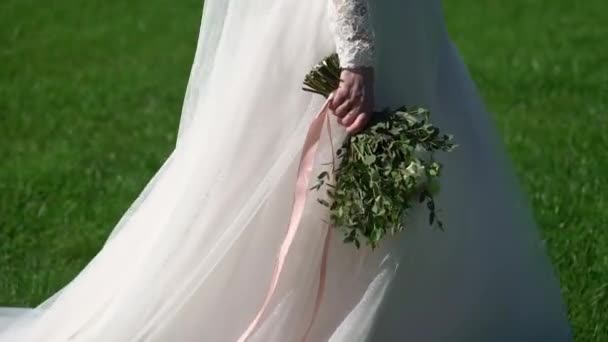 Giovane sposa in abito da sposa a piedi in un parco. Bianco moda abito di lusso — Video Stock
