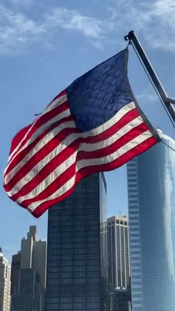 La bandera estadounidense ondea contra el telón de fondo de los rascacielos en Nueva York EE.UU. . — Vídeo de stock