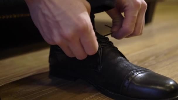 Az ember cipőt vesz fel és cipőfűzőt köt. — Stock videók