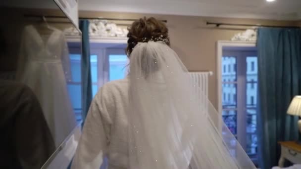 Nevěsta s dlouhým závojem se připravuje ráno. Příprava před svatebním obřadem, oblečte si šaty — Stock video