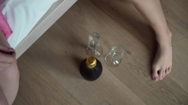 Dos novias jóvenes en el dormitorio toman una botella de champán y dos copas. despedida de soltera — Vídeo de stock