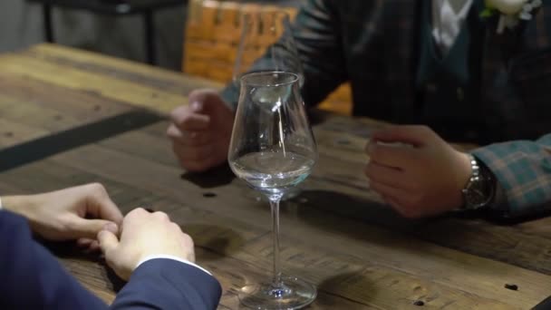 Двоє молодих чоловіків п'ють, сидячи за столом в барі, кафе або ресторані — стокове відео