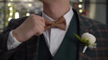 Groom fixing brown bowtie