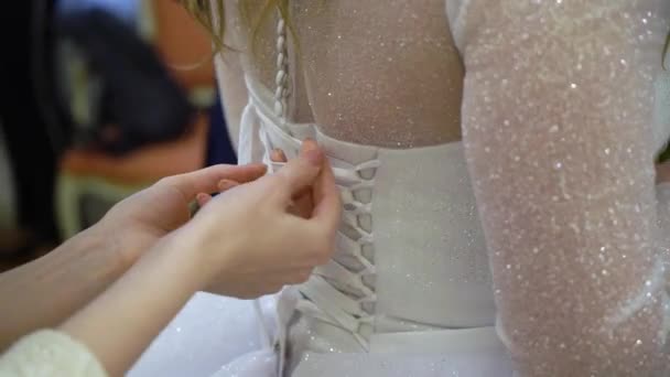 Demoiselle d'honneur aidant la jeune mariée à mettre sa robe de mariée. Robe de mariée de luxe — Video