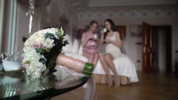 Dvě dívky pijící čaj nebo kávu v ložnici. Nevěsta a družička ve svatebním ránu — Stock video