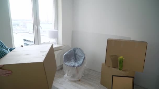Moving into a new home. A woman carries a box cardboard, apartment owner — Stock Video