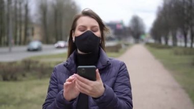 Cep telefonu olan bir şehirde koruyucu maskeli bir kadın. covid-19 koronavirüs