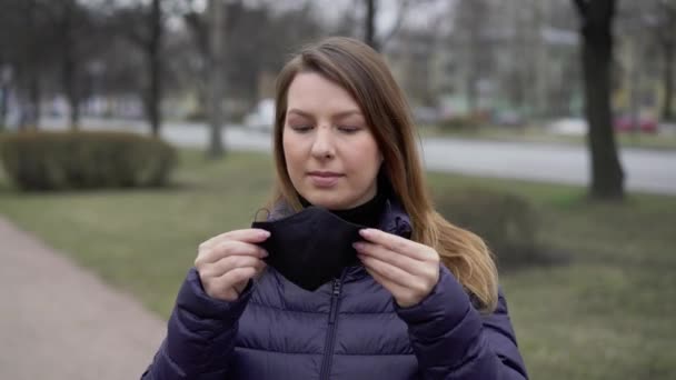 Uma mulher colocou uma máscara protectora numa cidade. Vírus da coronária epidémico covid-19 — Vídeo de Stock