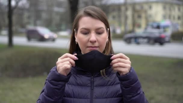 Egy nő arcvédő maszkot visel egy városban. Járványos covid-19 koronavírus — Stock videók