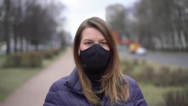 Kvinna i ansiktet skyddande mask i en stad. Epidemiskt pandemiskt covid-19-koronavirus — Stockvideo