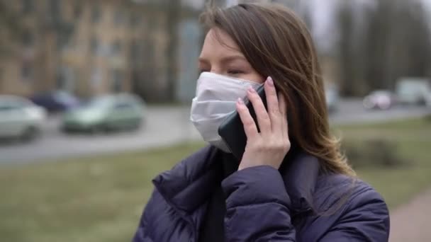 Wanita bertopeng pelindung di kota dengan ponsel. covid-19 coronavirus — Stok Video