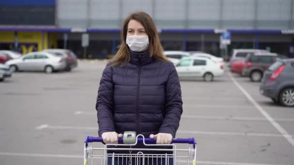 Mujer con máscara protectora facial en un carrito de supermercado en covid-19 coronavirus — Vídeo de stock