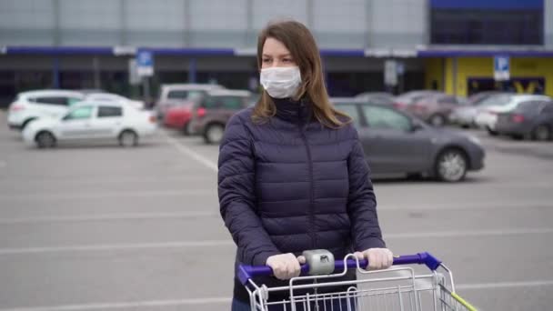 Mujer con máscara protectora facial en un carrito de supermercado en covid-19 coronavirus — Vídeo de stock