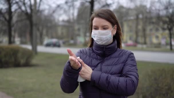 Γυναίκα σε πρόσωπο προστατευτική μάσκα σε μια πόλη με απολυμαντικό χεριών covid-19 coronavirus — Αρχείο Βίντεο