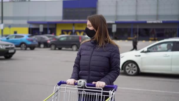 Женщина в защитной маске в тележке супермаркета на коронавирусе ковид-19 — стоковое видео
