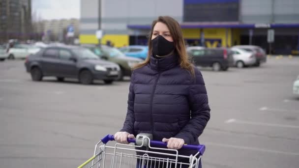 Femeia în mască de protecție a feței într-un coș de magazin de supermarket la coronavirus covid-19 — Videoclip de stoc