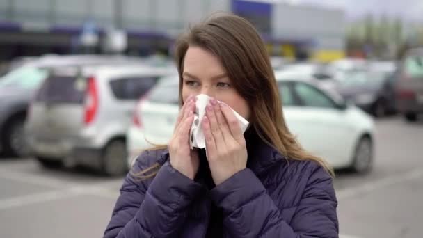 Kvinnan blåser näsan i en pappershandduk på en gata. Epidemiskt covid-19-koronavirus — Stockvideo