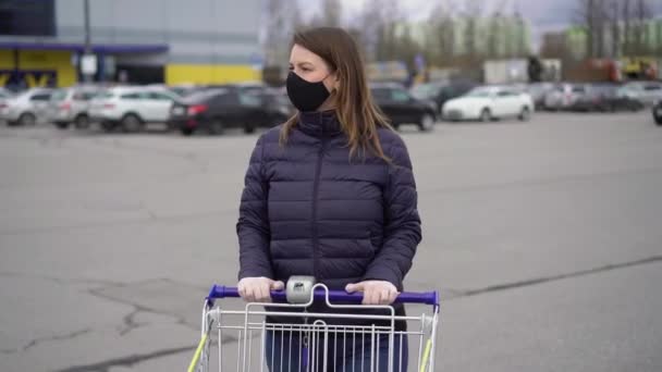 Mulher no rosto máscara protetora em um carrinho de supermercado na covid-19 coronavirus — Vídeo de Stock