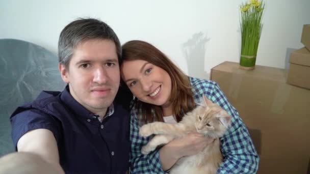 Pareja joven con gato tomando selfie en el teléfono móvil. Mover nuevo apartamento a casa — Vídeo de stock