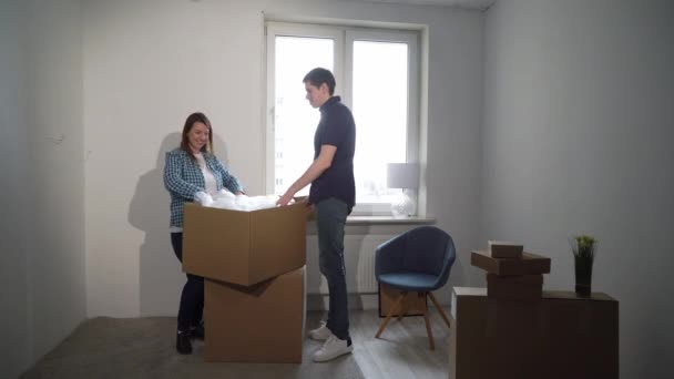 Yeni bir eve taşınıyorum. Aile bir karton kutuyu açıyor, apartman sahibi — Stok video