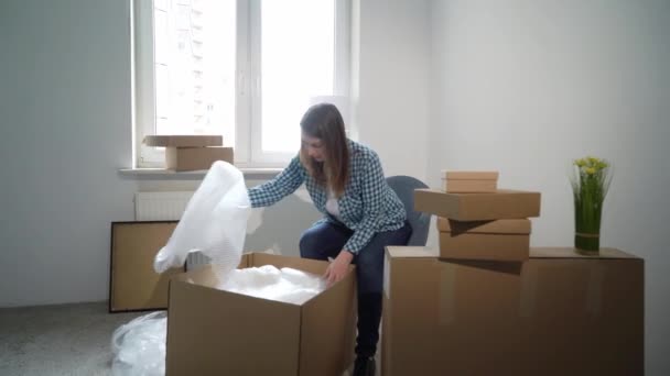 A mudar-se para uma nova casa. Mulher abrindo uma caixa de papelão, proprietário do apartamento — Vídeo de Stock