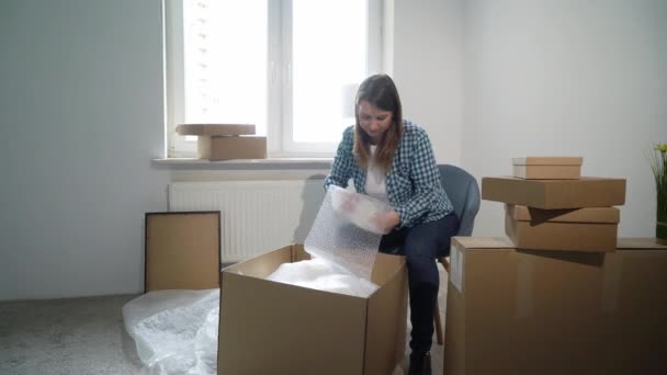 A mudar-se para uma nova casa. Mulher abrindo uma caixa de papelão, proprietário do apartamento — Vídeo de Stock