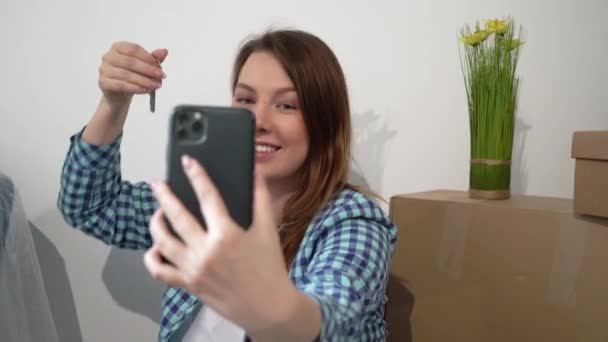 O tânără își face selfie pe telefonul mobil. Mutarea apartamentului nou acasă, cutii — Videoclip de stoc