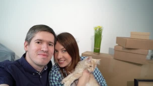 Junges Paar mit Katze macht Selfie mit Handy. Umzug in neue Wohnung — Stockvideo