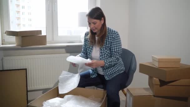 Moving into a new home. Woman opening a box cardboard, apartment owner — Stock Video