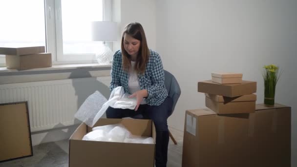 A mudar-se para uma nova casa. Mulher abrindo uma caixa de papelão, proprietário do apartamento — Vídeo de Stock