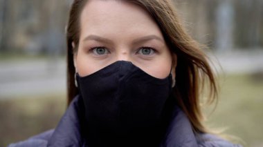 Şehirde koruyucu maskeli bir kadın. Salgın salgın covid-19 coronavirüs