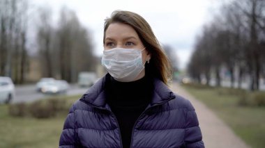 Şehirde koruyucu maskeli bir kadın. Salgın salgın covid-19 coronavirüs