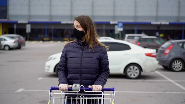 Covid-19 Coronavirus 'taki süpermarket arabasında koruyucu maskeli bir kadın.