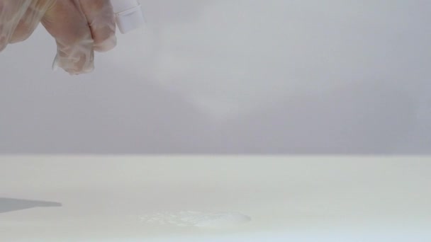Жінка в захисних рукавичках прибирає білий стіл з тканиною і спреєм . — стокове відео