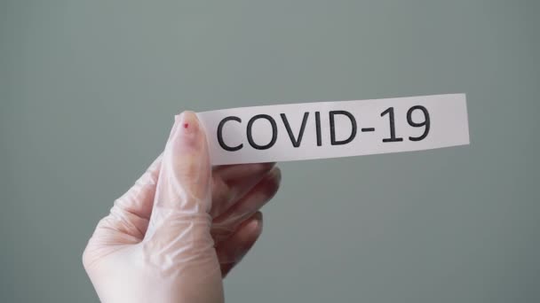 Femeie în mănuși de protecție din latex care deține hârtie cu text covid-19 coronavirus — Videoclip de stoc