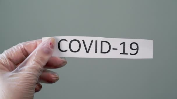 Mulher em luvas protetoras de látex segurando papel com texto de coronavírus covid-19 — Vídeo de Stock