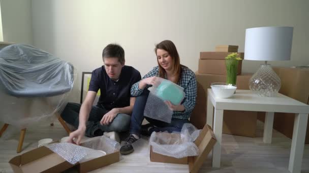 Umzug in ein neues Zuhause. Paar packt Geschirr in Karton, Wohnungseigentümer — Stockvideo