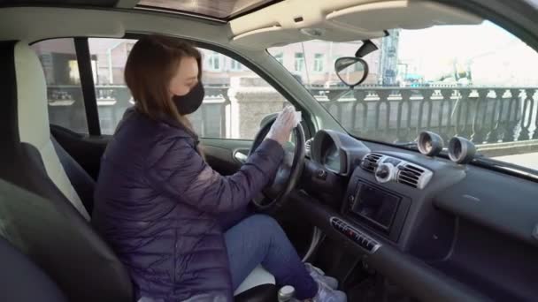 Jovem mulher limpa volante whell de carro em luvas de proteção . — Vídeo de Stock