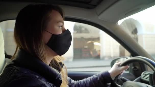 Wanita muda mengendarai mobil dengan sarung tangan pelindung. Pandemik dari coronavirus covid-19. — Stok Video