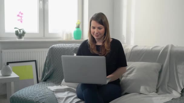 Молодая женщина дистанционно работает дома с ноутбуком. Коронавирус Ковида-19 — стоковое видео