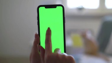 Yeşil ekran kromatonlu akıllı telefon, elinde tutan ve kullanan kadın.