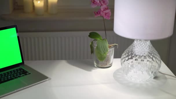 Ordenador portátil portátil con pantalla verde en la mesa en la oficina en casa por la noche — Vídeos de Stock