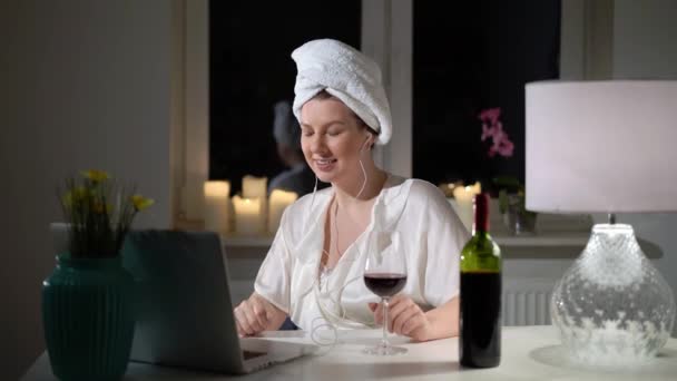 Giovane donna che lavora al computer portatile a casa sera con vino, videochiamata — Video Stock