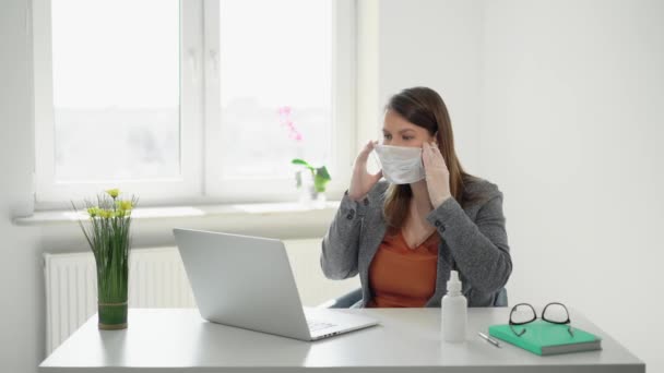 Jonge vrouw werkt op laptop computer met kantoormasker tijdens epidemie covid-19 — Stockvideo