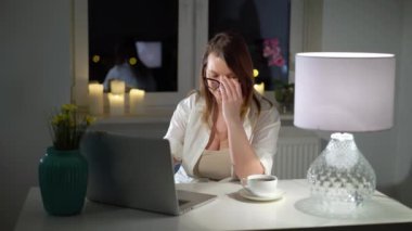 Akşamları evdeki bilgisayarda çalışan genç bir kadın.