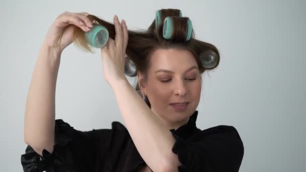 Chica usando rizador en el pelo, hace peinado. Mujer joven en ropa interior de albornoz . — Vídeo de stock
